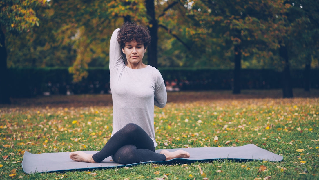 Woman doing yoga pose on mat in park