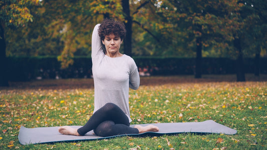 Woman doing yoga pose on mat in park