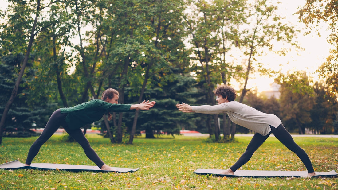 Two people doing yoga in a park