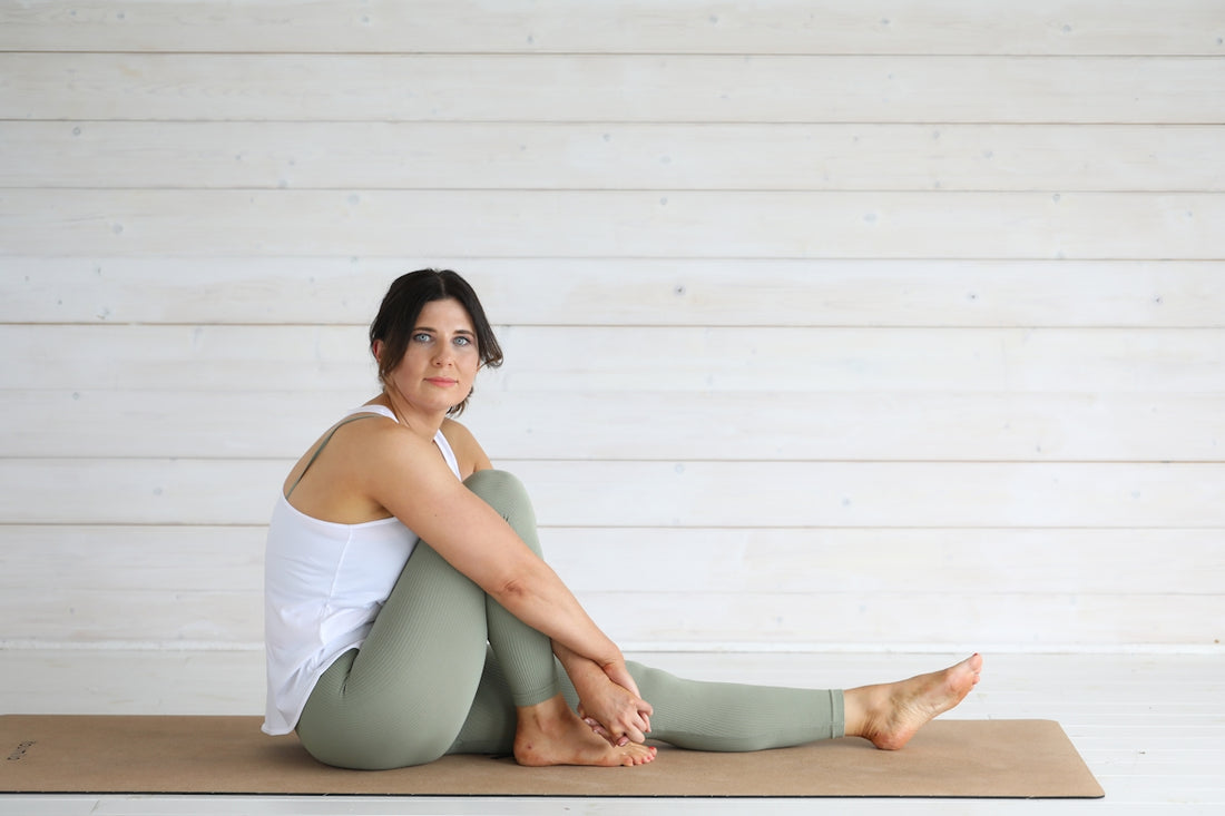 Woman in yoga pose on mat against white wall