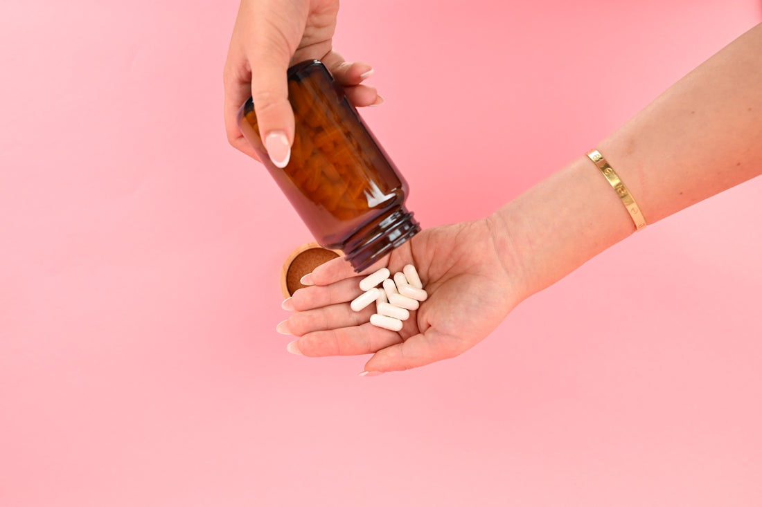 Person pouring white pills from bottle into hand