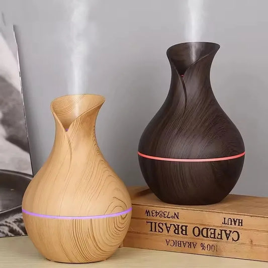 Two wooden-textured diffusers, one brown and one beige, on a wooden block with a blurred background.